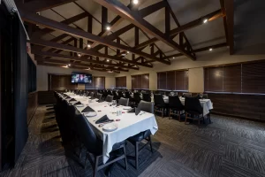Side-angle view of a formal banquet room with a long table layout, emphasizing the architectural details of the wooden vaulted ceiling and professional table settings.