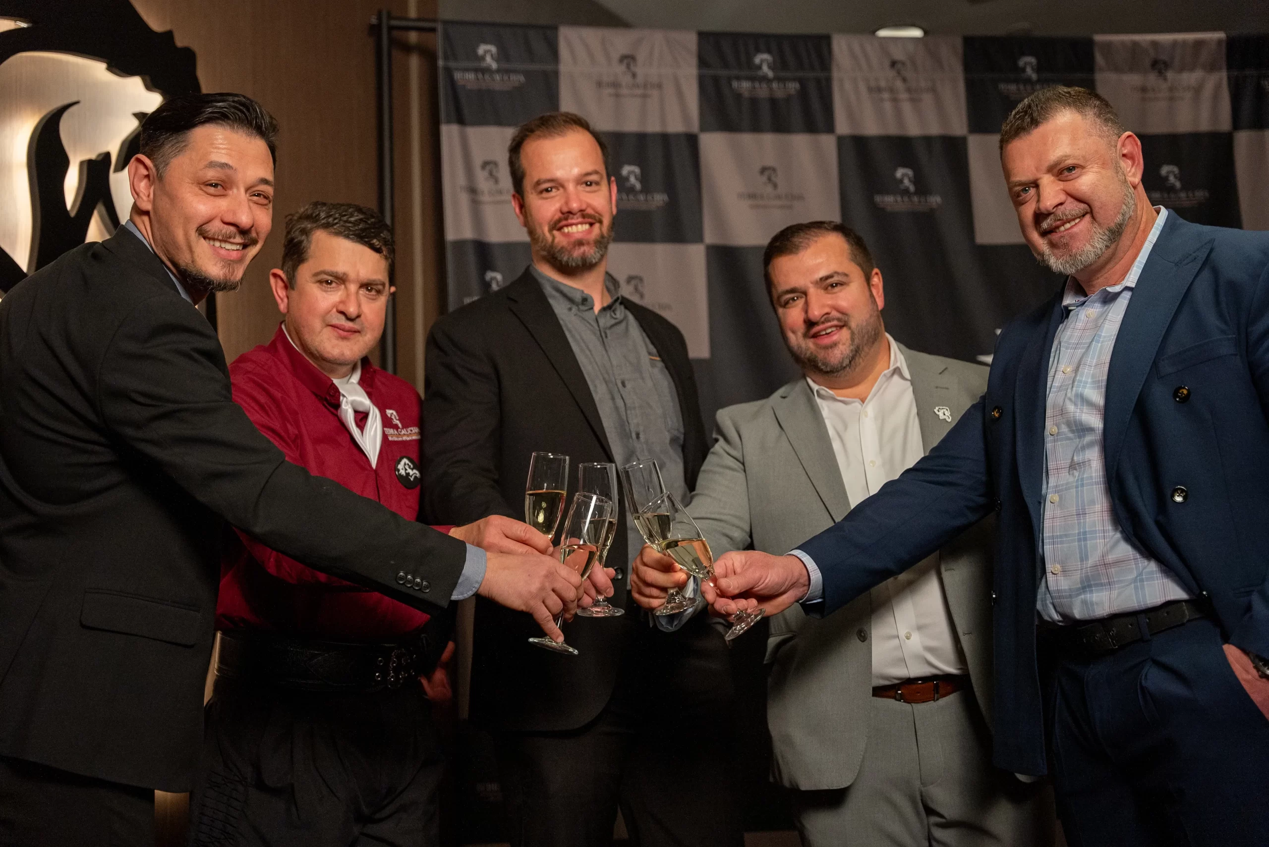 Group of five men toasting with drinks at a formal event.