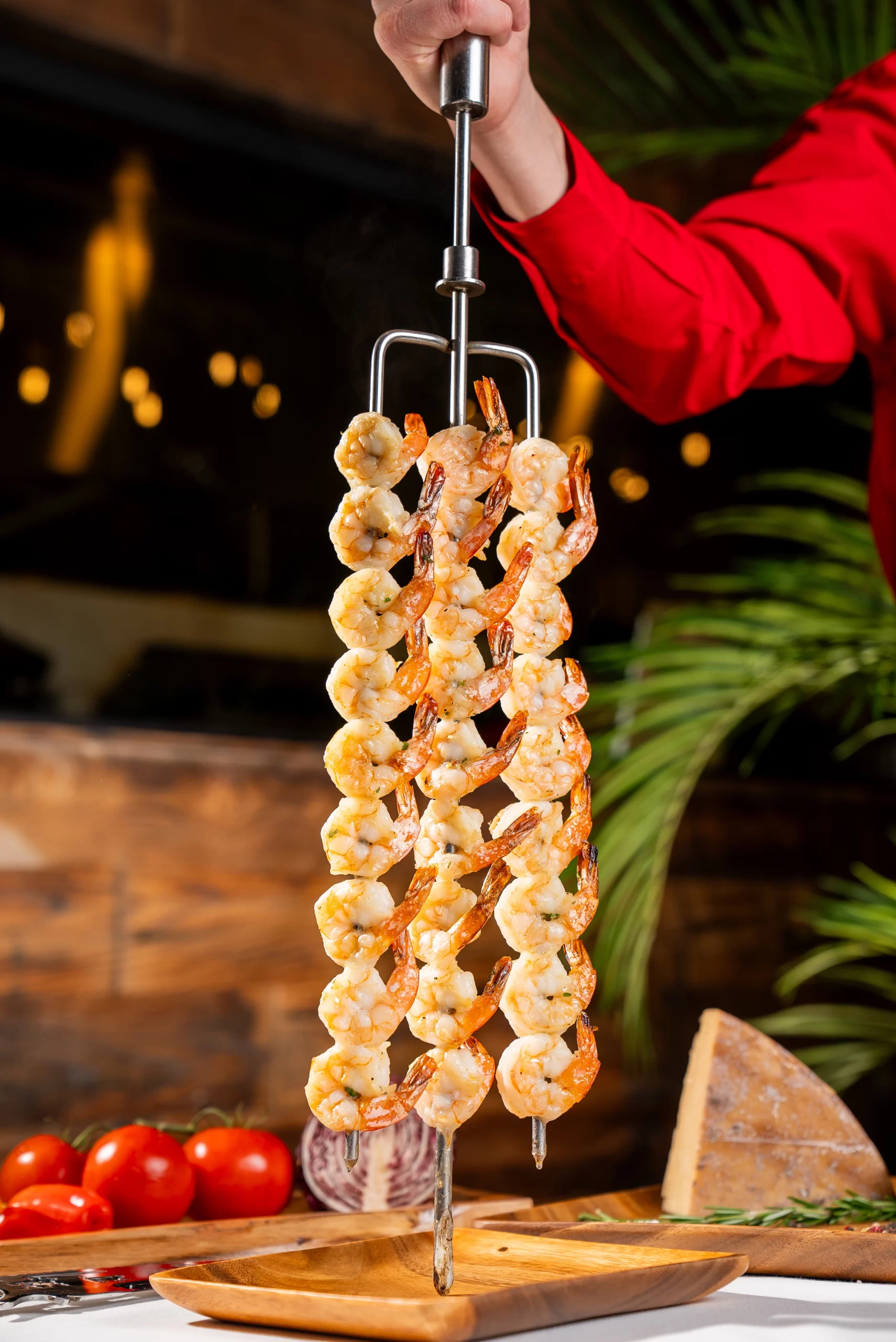Skewered grilled lamb chops, each with a bone, held by a server in a red shirt. Skewered grilled lamb chops, each with a bone, held by a server in a red shirt.